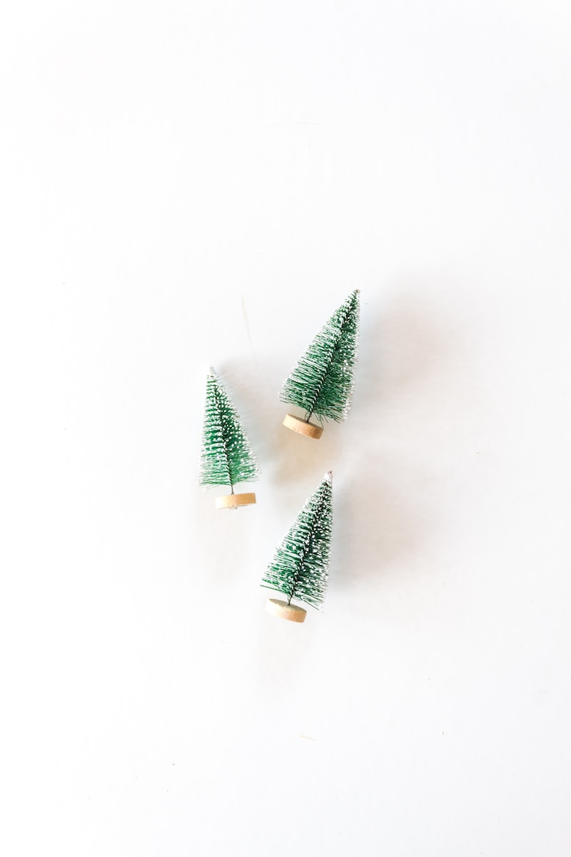 three pine tree miniatures on white surface