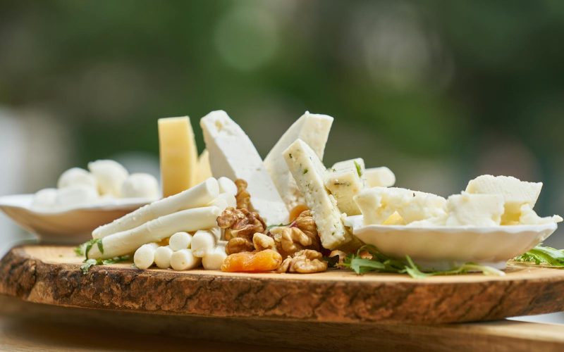 A delicious assortment of cheese and nuts on a rustic wooden board, perfect for appetizers.